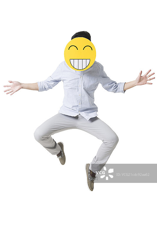 年轻男子戴着卡通笑脸跳跃图片素材