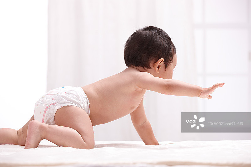 一个婴儿趴在室内床上图片素材