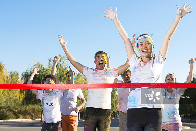 Young woman crossing finishing line at The Color Run图片素材