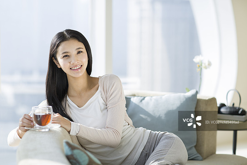 快乐的年轻女子喝红茶图片素材