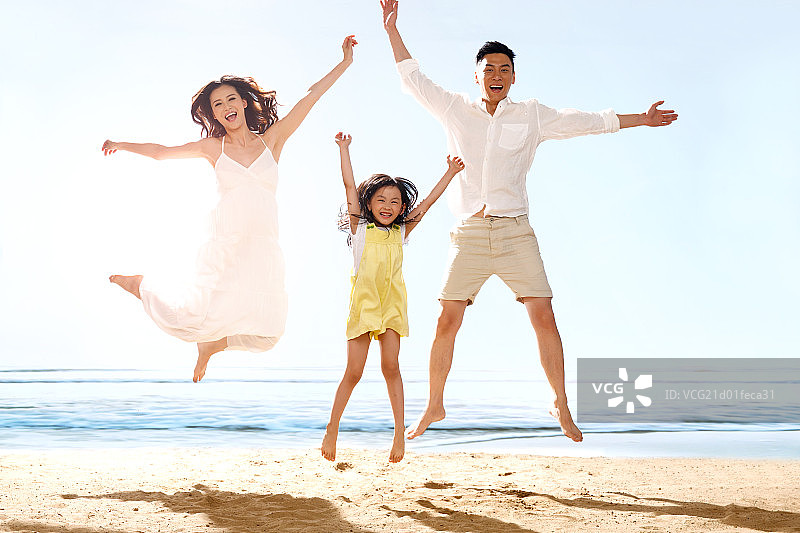 快乐的一家三口在海边跳跃图片素材