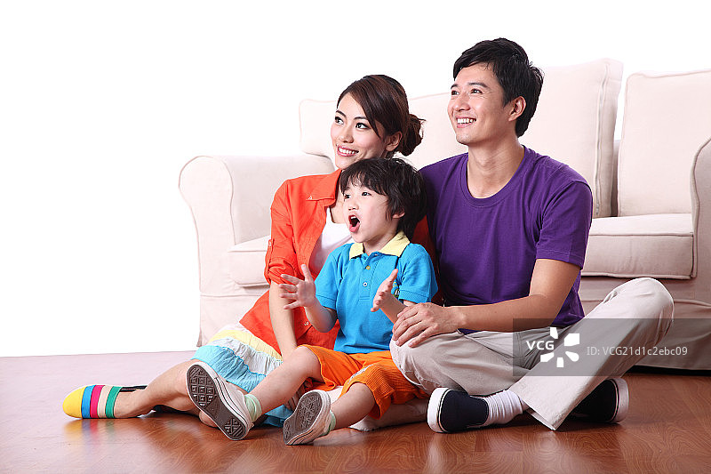 坐在地板上看电视的一家三口图片素材