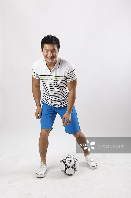 一个穿休闲装踢足球的青年男士图片素材