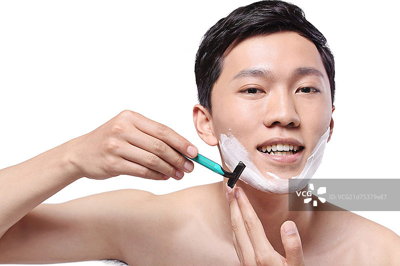 白色背景下面容清爽手拿剃须刀的亚洲男青年图片素材