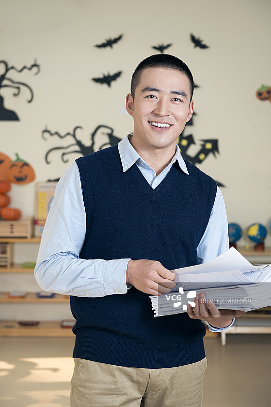 Male kindergarten teacher holding books图片素材