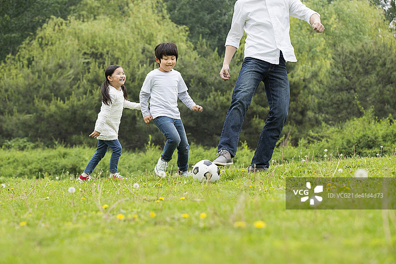 父亲和孩子们一起踢足球图片素材