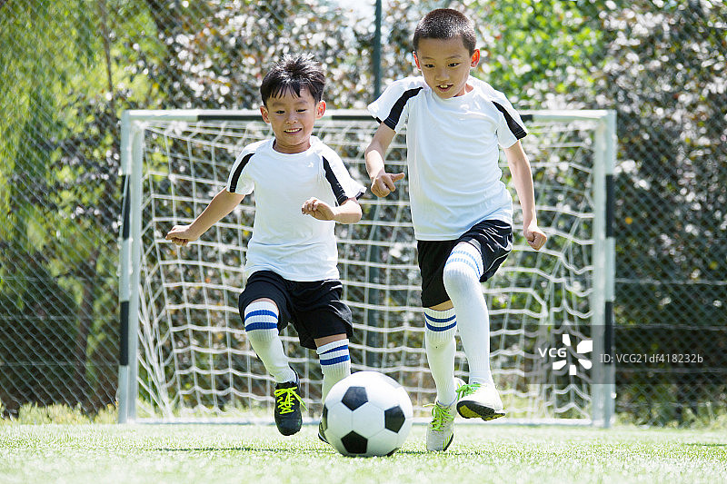 两个男孩在足球场上踢球图片素材