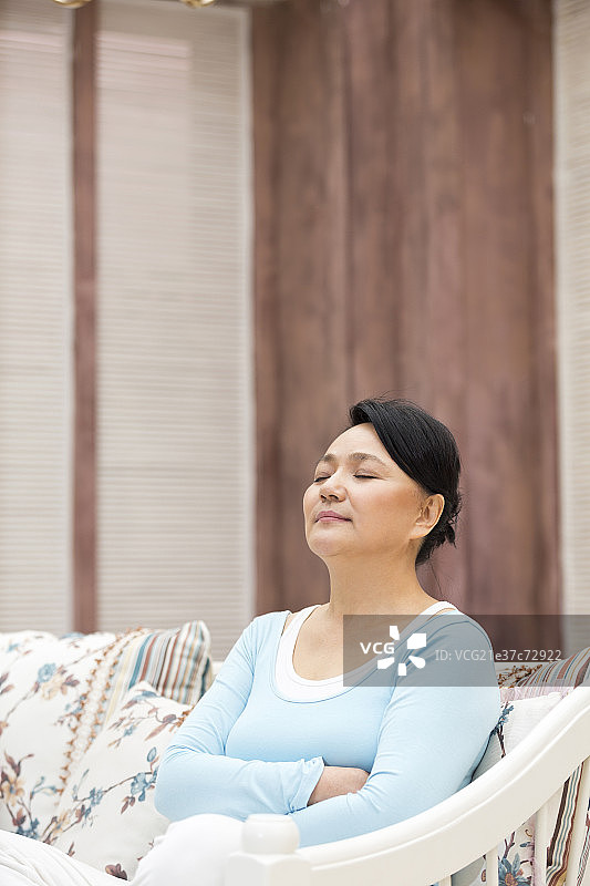 快乐的中年女人坐在沙发上图片素材