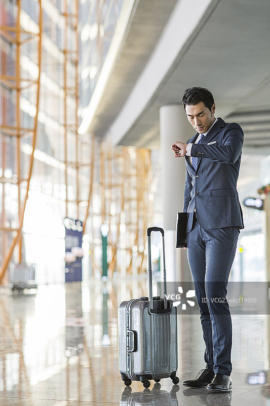 年轻商务男士在机场看手表时间图片素材