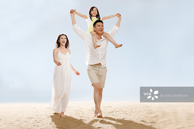 快乐的一家三口在海边玩耍图片素材