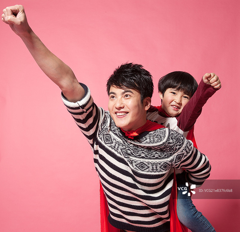 父亲背着儿子在模仿超人起飞图片素材