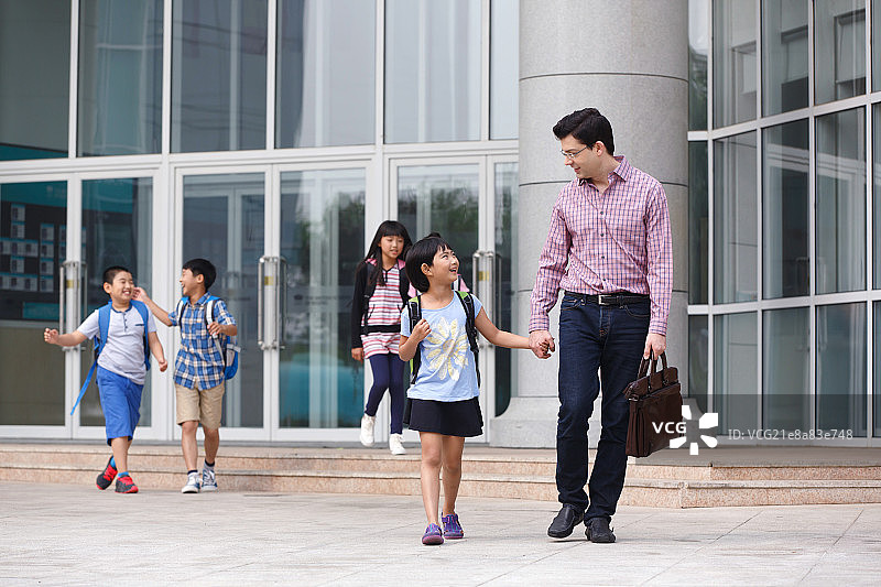 父亲牵着女儿的手从教学楼里出来图片素材