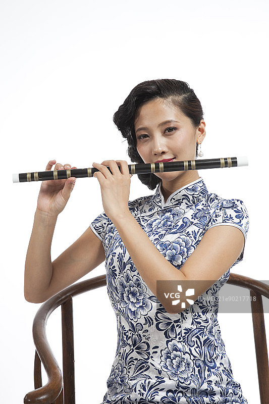 棚拍身穿中国传统服装的年轻女人吹箫图片素材