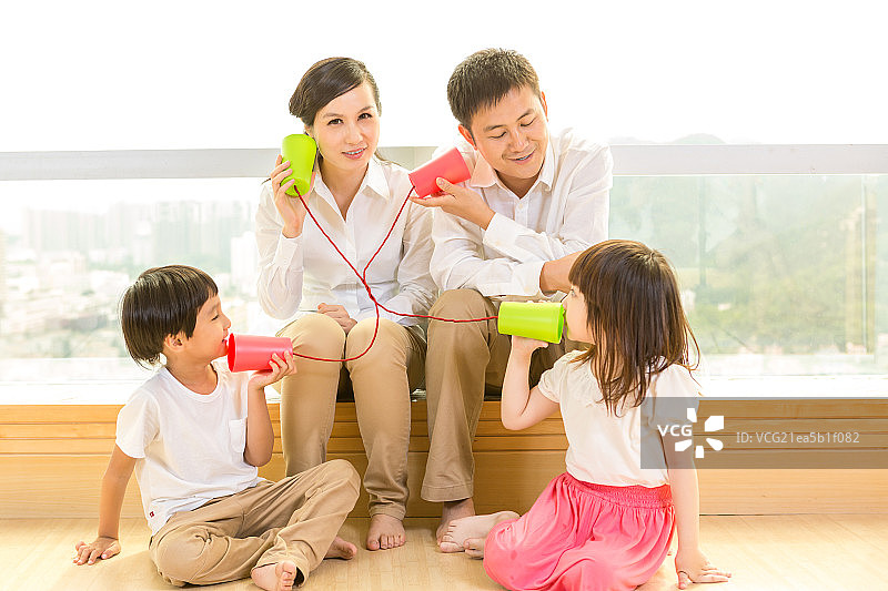 一家人在家里玩土电话图片素材