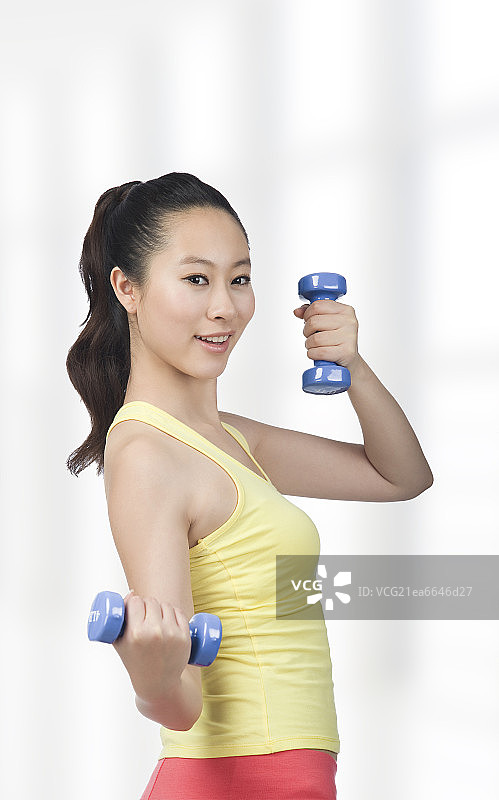 棚拍年轻女人举哑铃图片素材