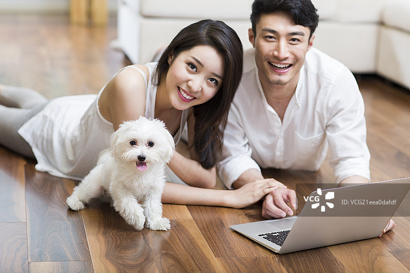 年轻情侣趴在地板上使用平板电脑图片素材