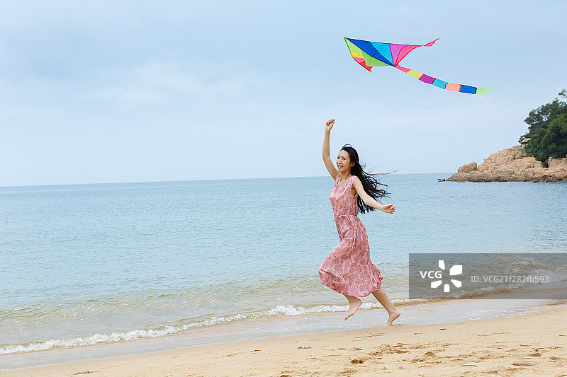 年轻女孩在海边放风筝图片素材