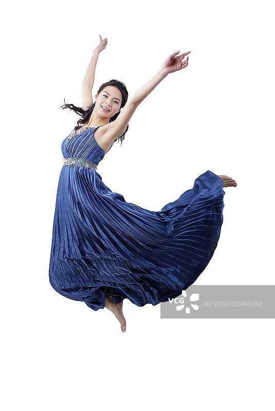 高举手臂身穿晚礼服跳跃起来的年轻女人图片素材