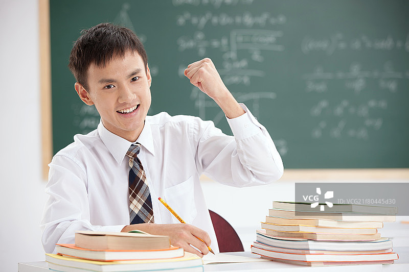 一个中学男生在教室里做握拳的手势图片素材