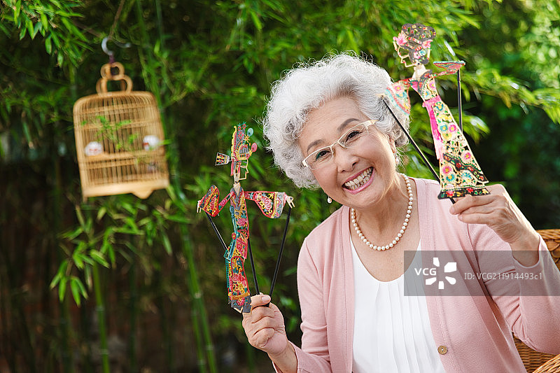 一个老年女人拿着皮影偶图片素材