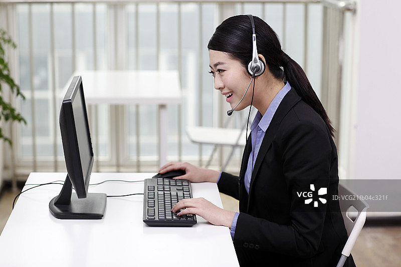 商务女士头戴耳机使用电脑图片素材