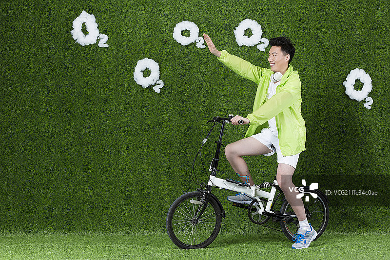 草地创意男青年骑自行车图片素材