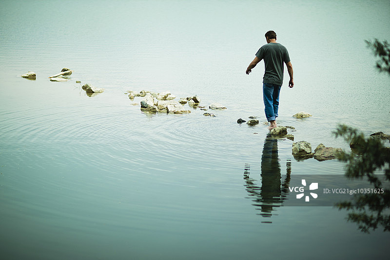 赤脚走过湖岸边石阶的男人图片素材