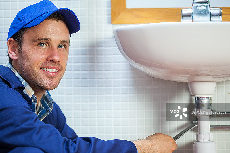 迷人而快乐的水管工在公共浴室修理水槽图片素材