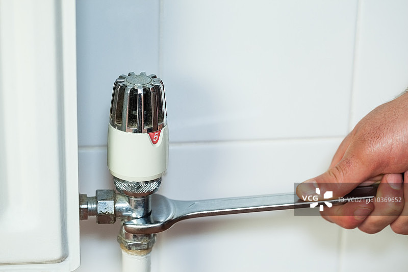 手持扳手修理散热器特写图片素材