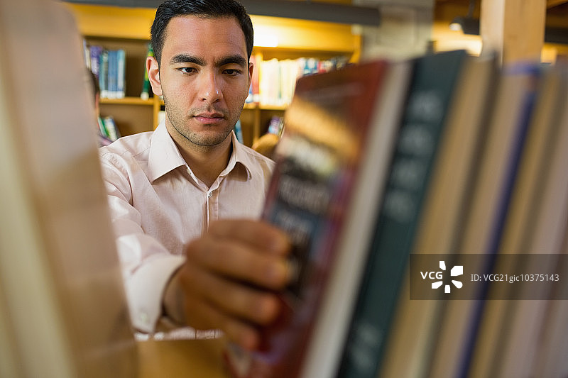 图书馆里一位表情严肃的年长学生在书架上选书的特写镜头图片素材