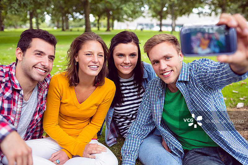 快乐的男人和他的大学朋友在公园里合影图片素材