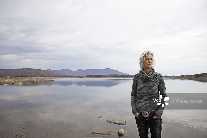 女人在平静的湖岸边眺望水面图片素材