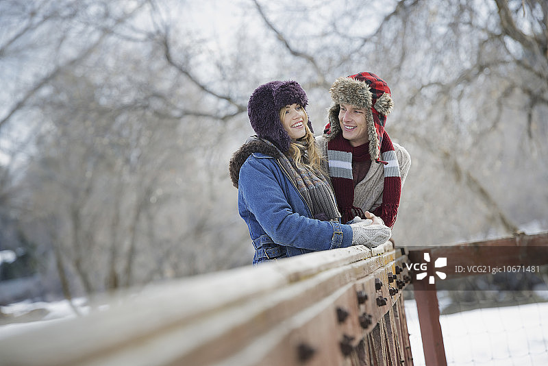 雪地冬景：情侣依偎在栅栏旁图片素材