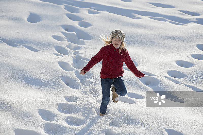 雪地冬景：女孩在厚厚的雪地里奔跑，留下脚印图片素材