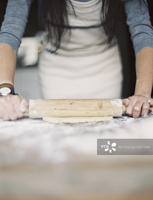 家常厨房：一位女士在桌子上擀面图片素材