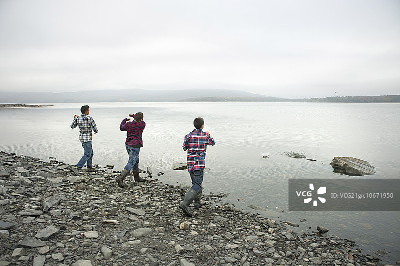 阿肖肯湖畔的一天：三个男孩在岸边扔石子图片素材