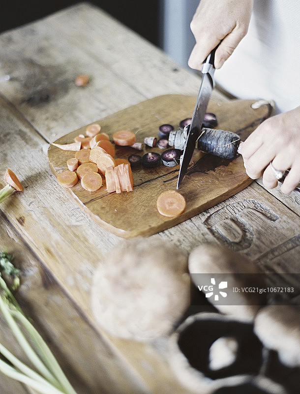 厨房台面：一人用刀在砧板上切新鲜蔬菜图片素材