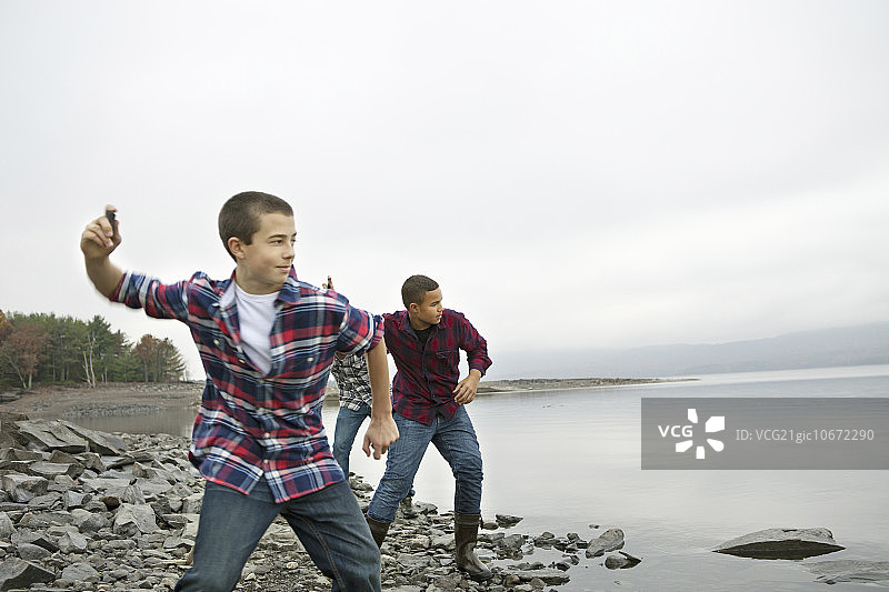 阿肖肯湖畔的一天：三个男孩在岸边扔石子图片素材