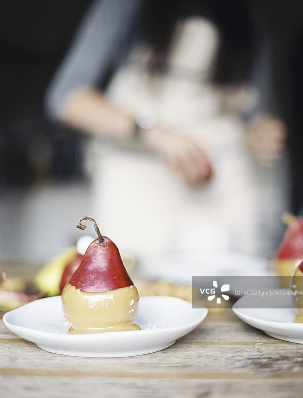 在家庭厨房里，一个女人将新鲜的有机梨蘸上甜点酱汁，然后放在盘子里图片素材