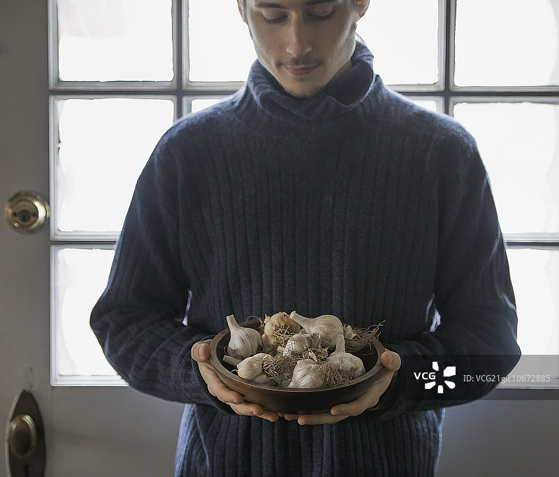 纽约州冬季有机农场：手捧大蒜的年轻男子图片素材