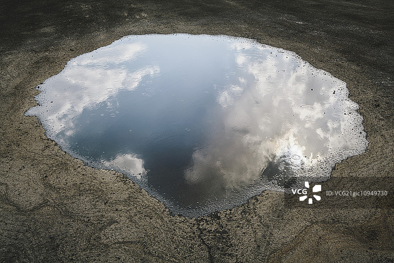 雨滴落在水坑中，天空云彩的倒影图片素材