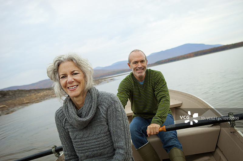 一对情侣，男女在秋日坐在水上的划艇里图片素材