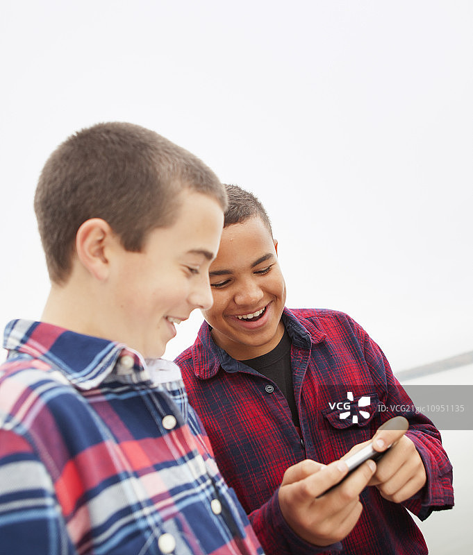 阿肖坎湖畔一日游：两个男孩在看手机屏幕图片素材