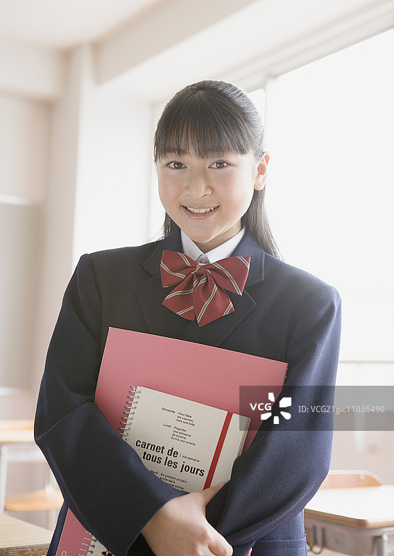 笑容灿烂的少女手拿教科书图片素材