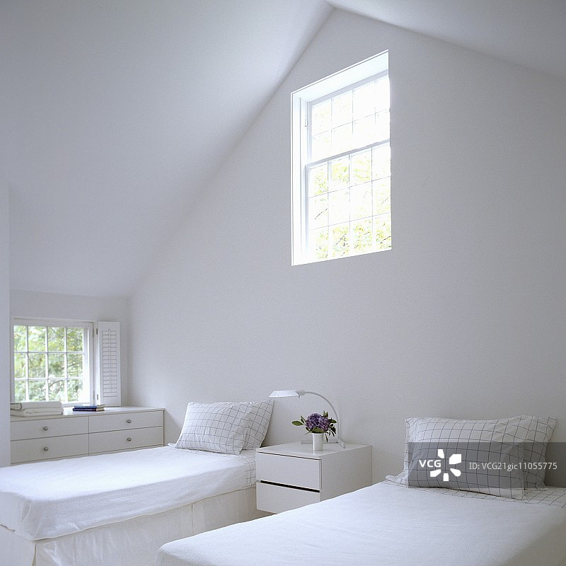 白色卧室：阁楼里的单人床，山墙墙壁上有一扇窗户图片素材