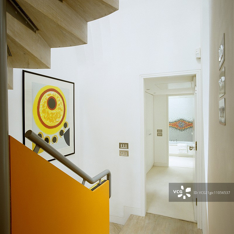 带有安装在橙色面板上的栏杆，以及透过敞开的门进入走廊的楼梯图片素材