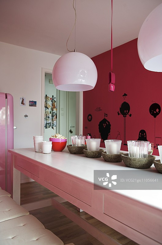 白色实木长餐桌与烛台，粉色墙壁上的黑色人像图片素材