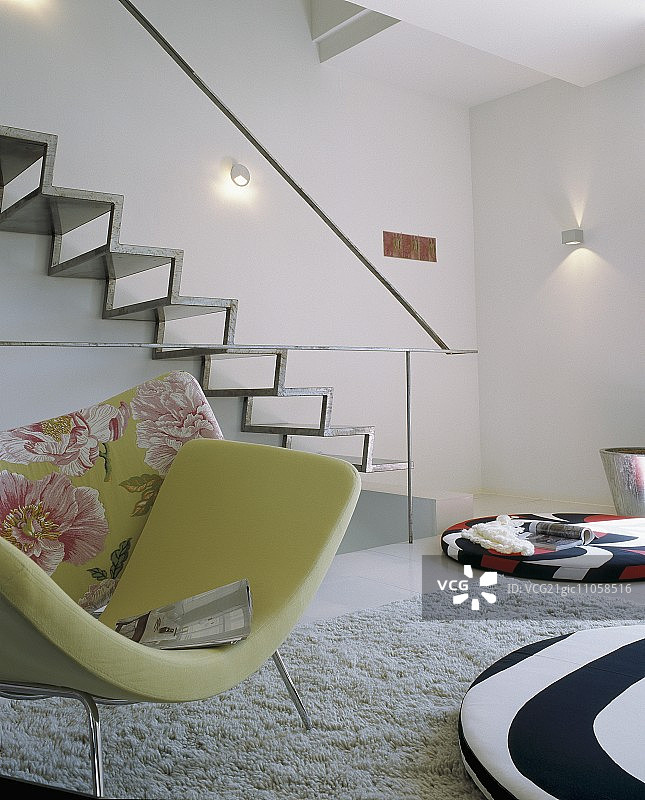 设计师室内，现代金属楼梯墙前带绿色椅套的扶手椅和彩色落地垫图片素材