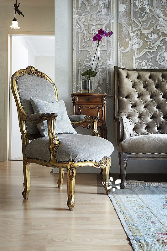 镀金洛可可扶手椅，浅蓝色天鹅绒内饰，位于小型古董柜前图片素材