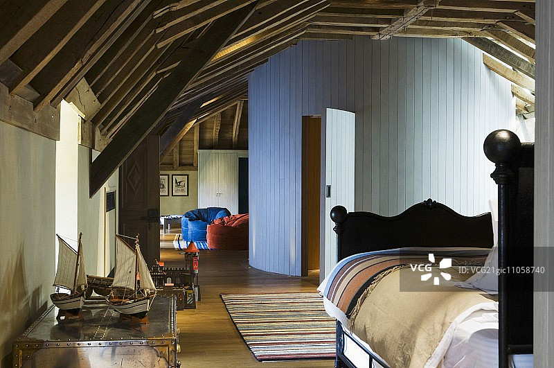 阁楼开放式房间内的雪橇床，通往白色木质圆形浴室图片素材